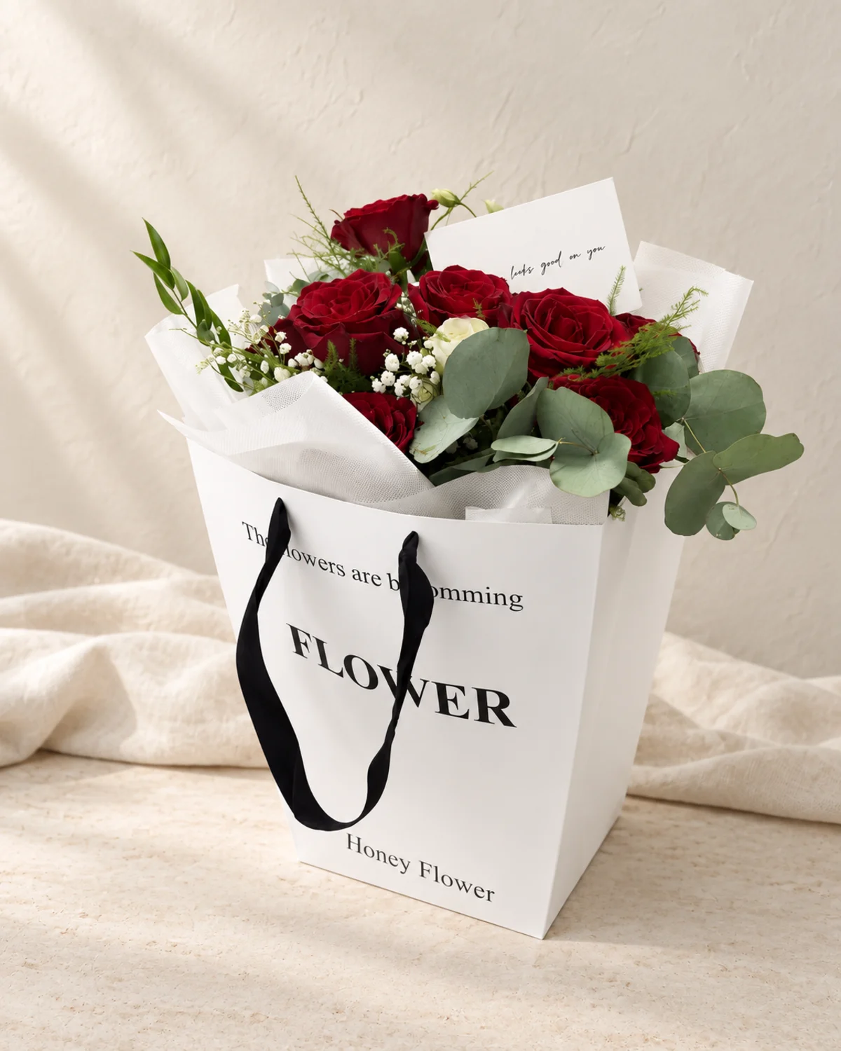 Red roses with gypsophila and eucalyptus in a white flower bag - flower delivery in Prilep