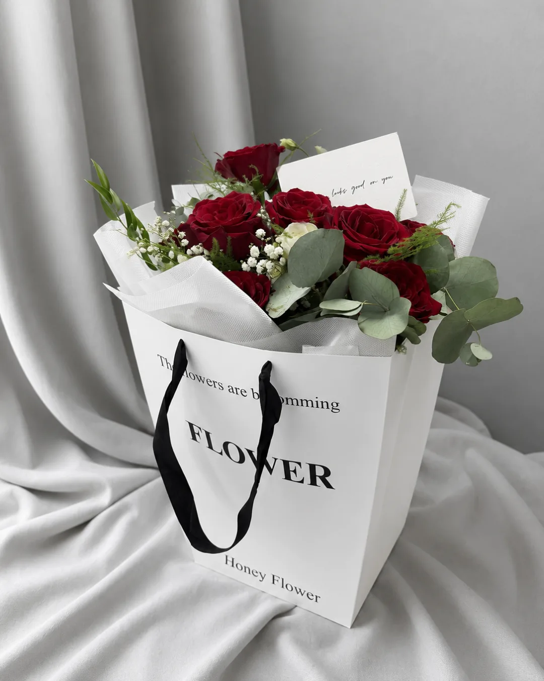 Red roses with gypsophila and eucalyptus in a white flower bag - flower delivery in Prilep